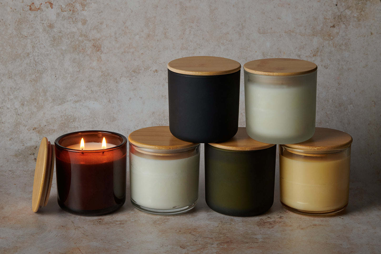 A group of large candles displayed on a beige background