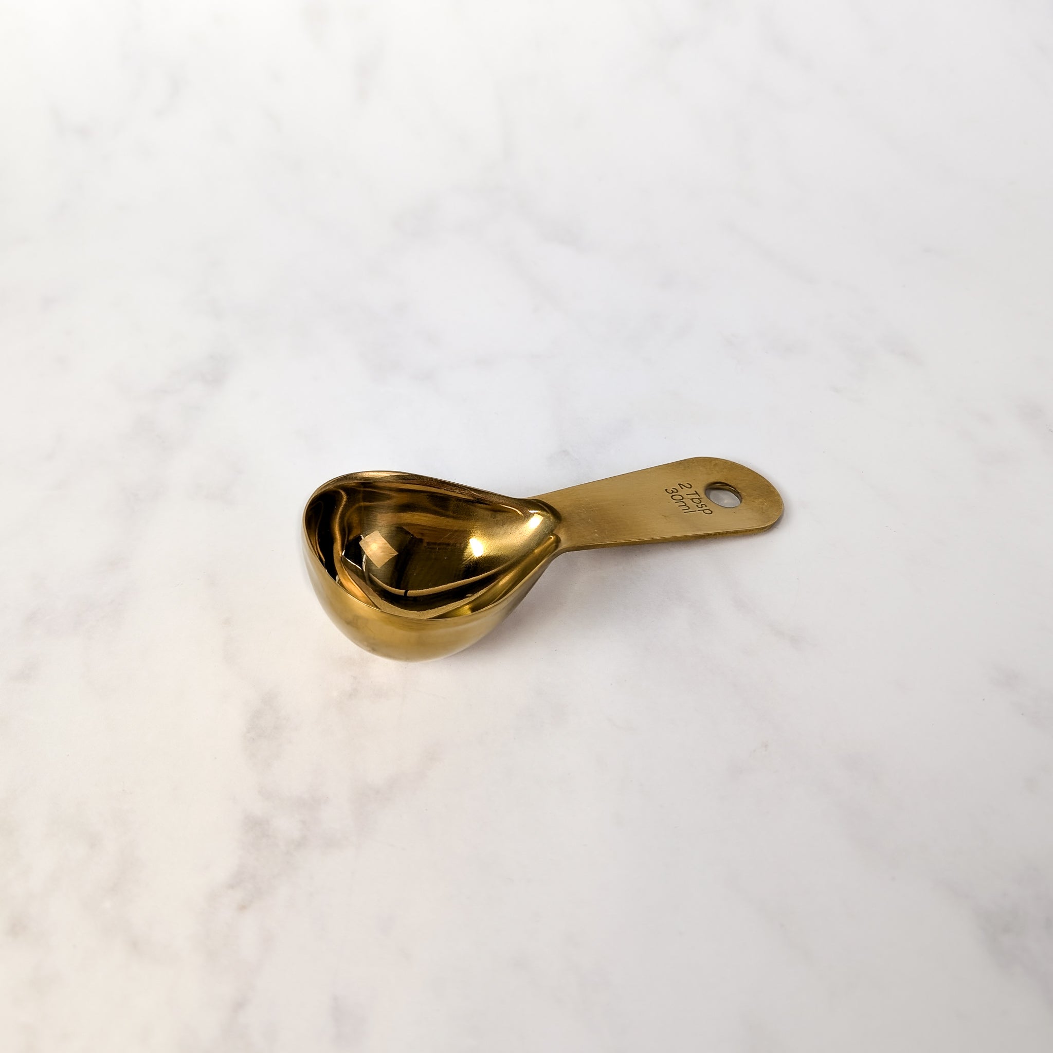 Gold measuring spoon on a white marble surface