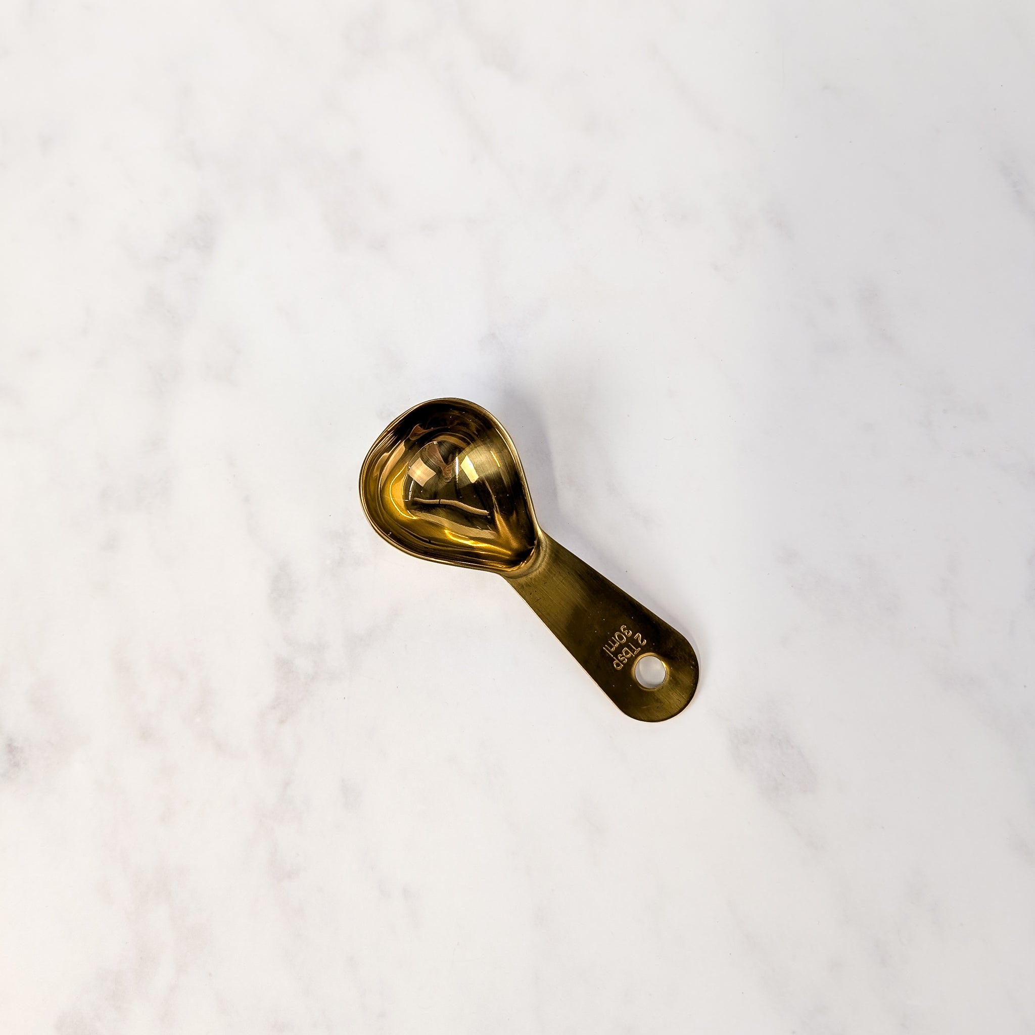 Gold measuring spoon on a white marble surface