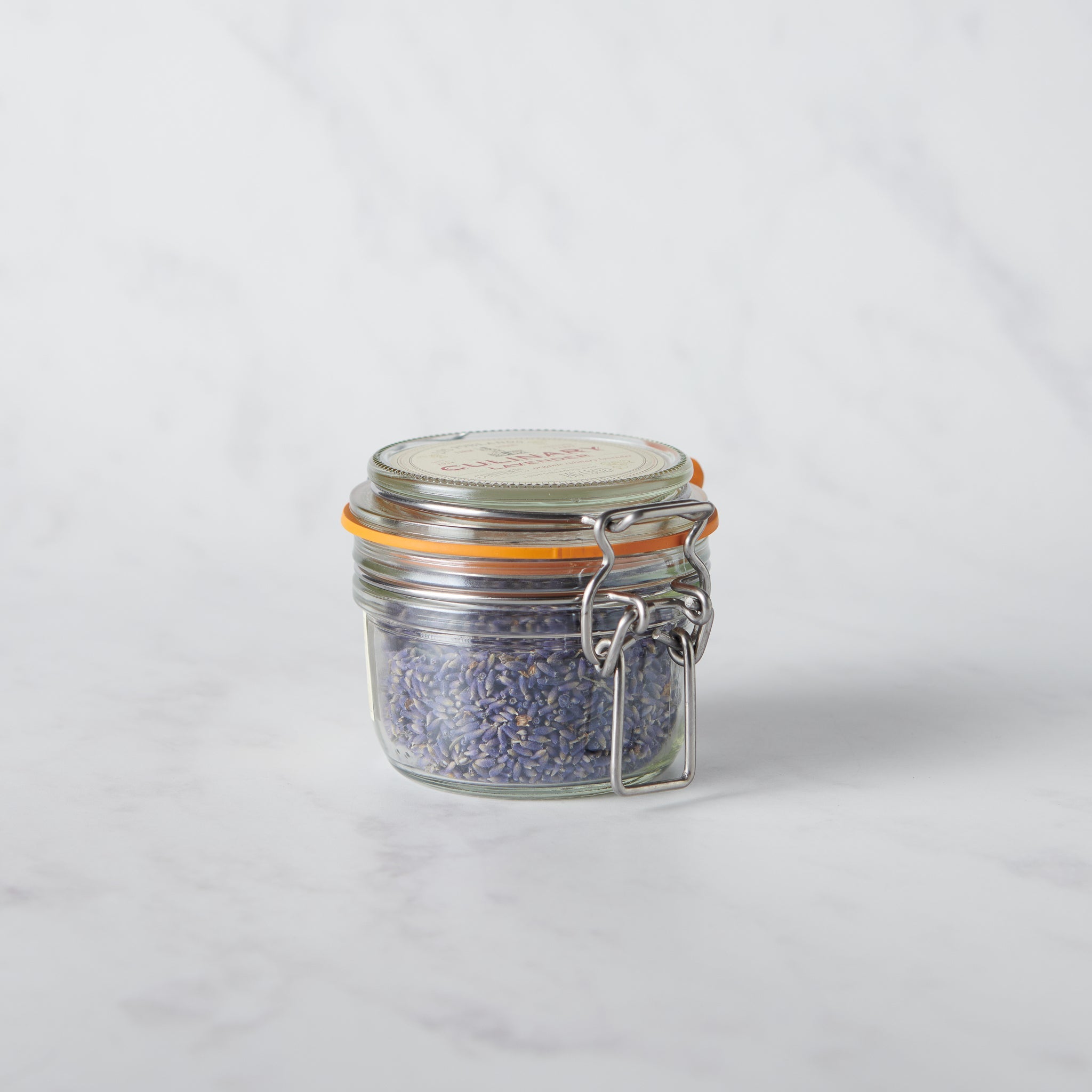 Small glass jar with metal lid containing a purple substance on a white background