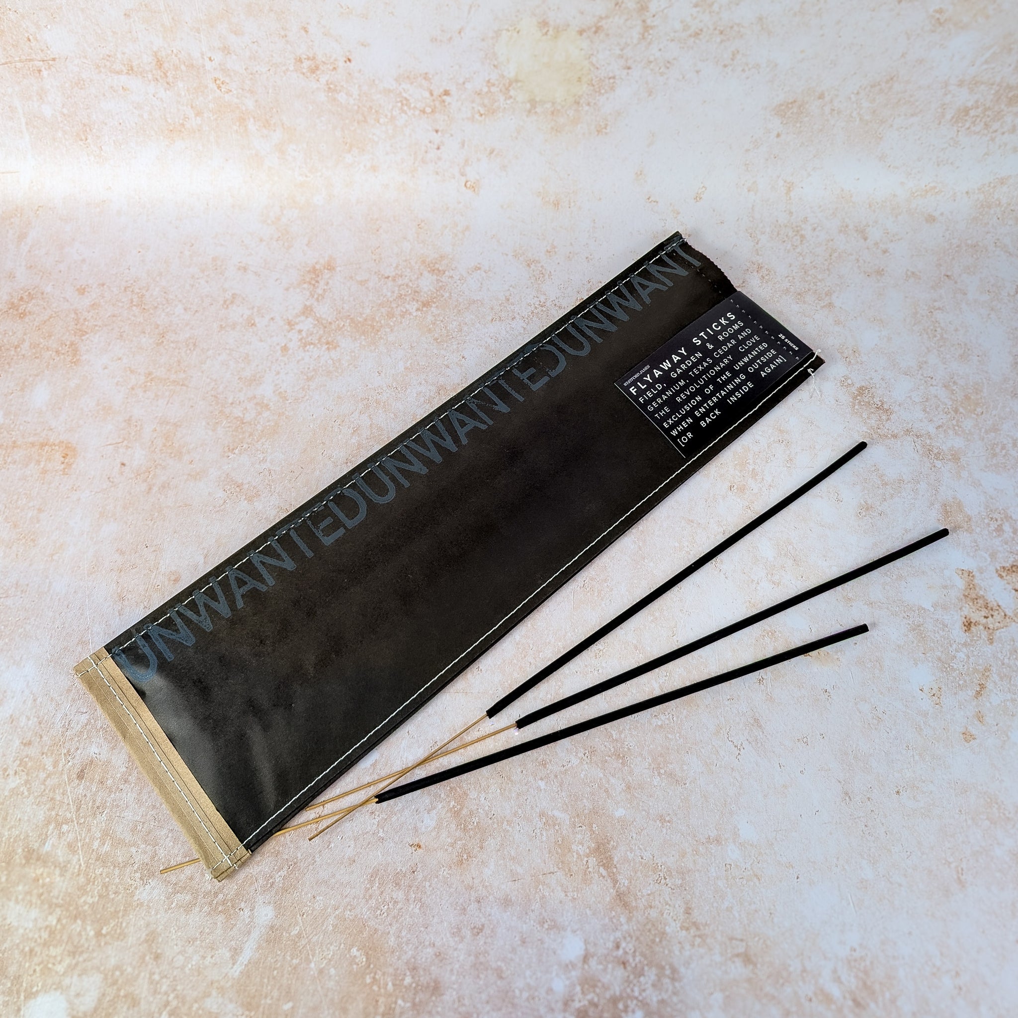 Black incense sticks in a holder on a beige surface