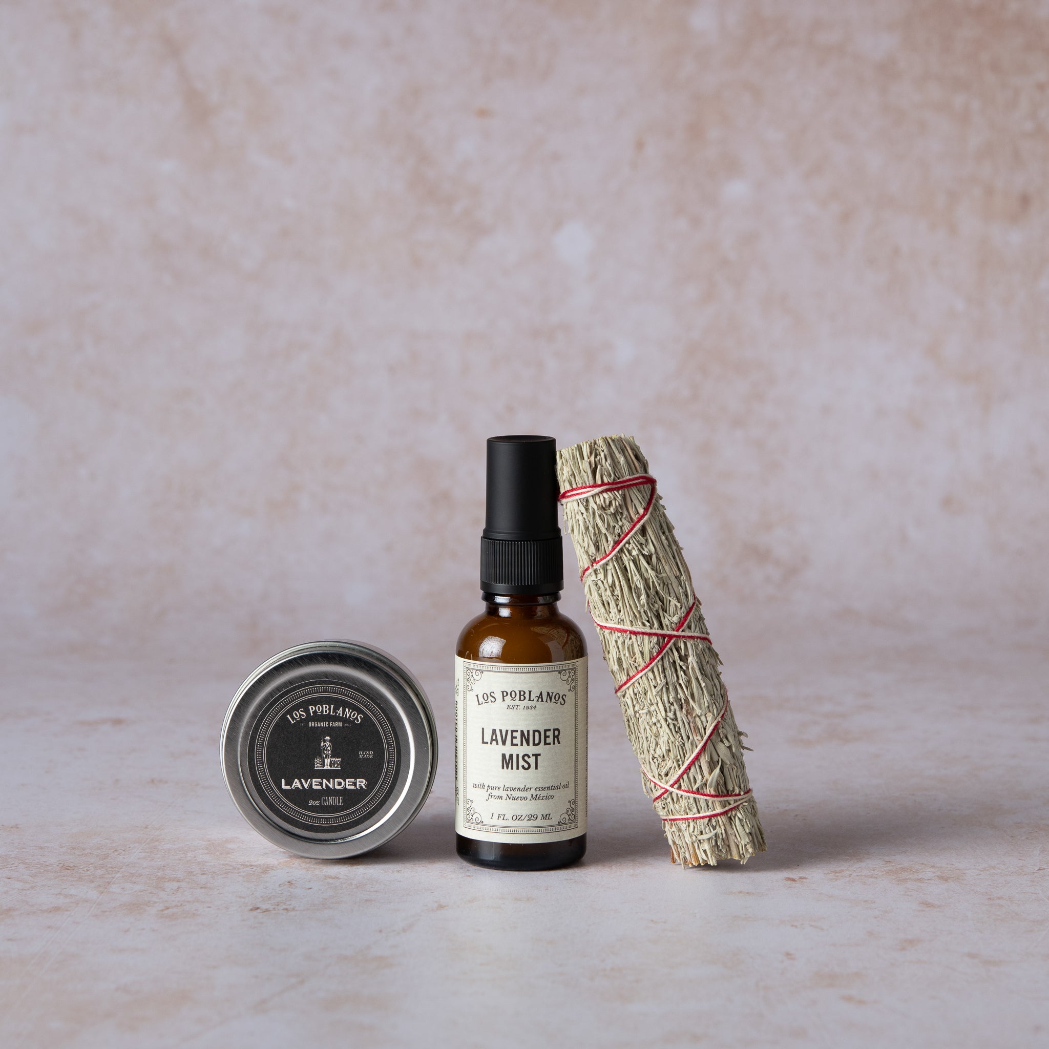 A set of three items including a lavender travel candle in a metal container, a lavender mist spray bottle, and a sage smudge stick, all packaged together.