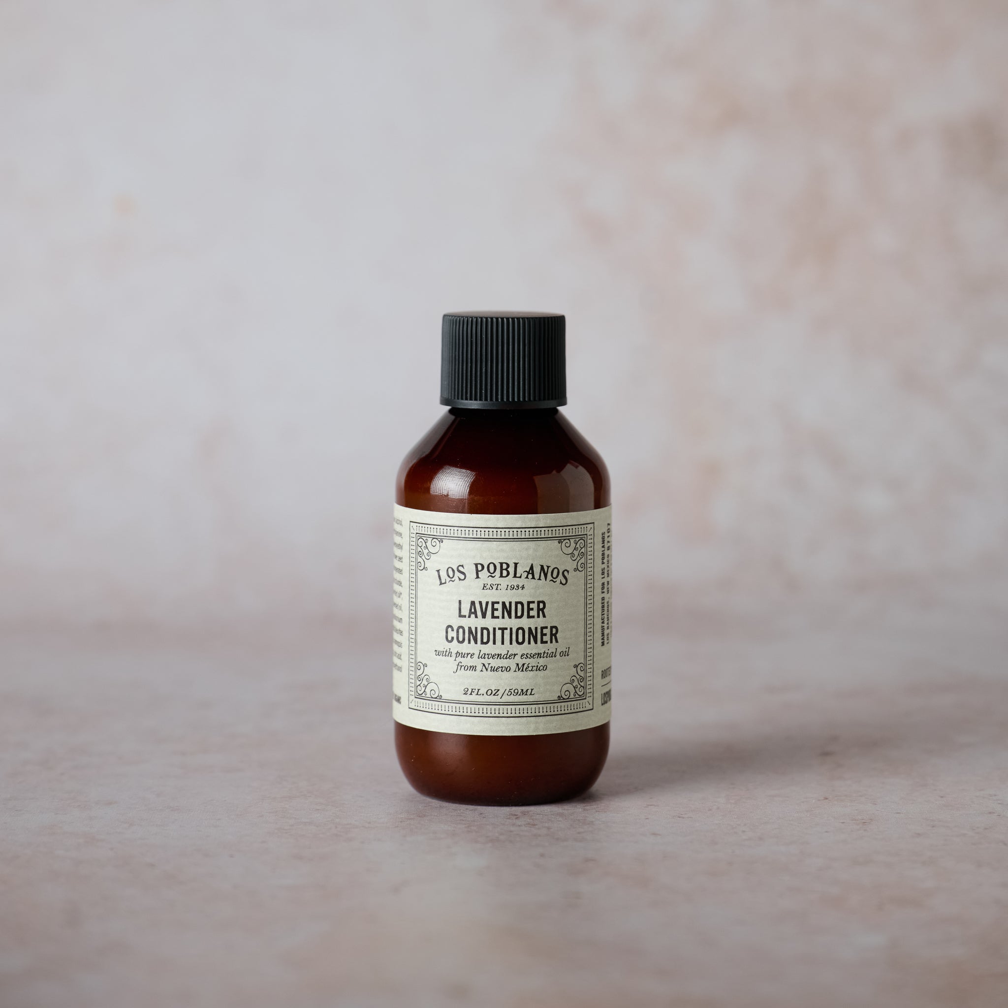 A brown bottle 'Los Poblanos Lavender Conditioner', set against a textured beige background.