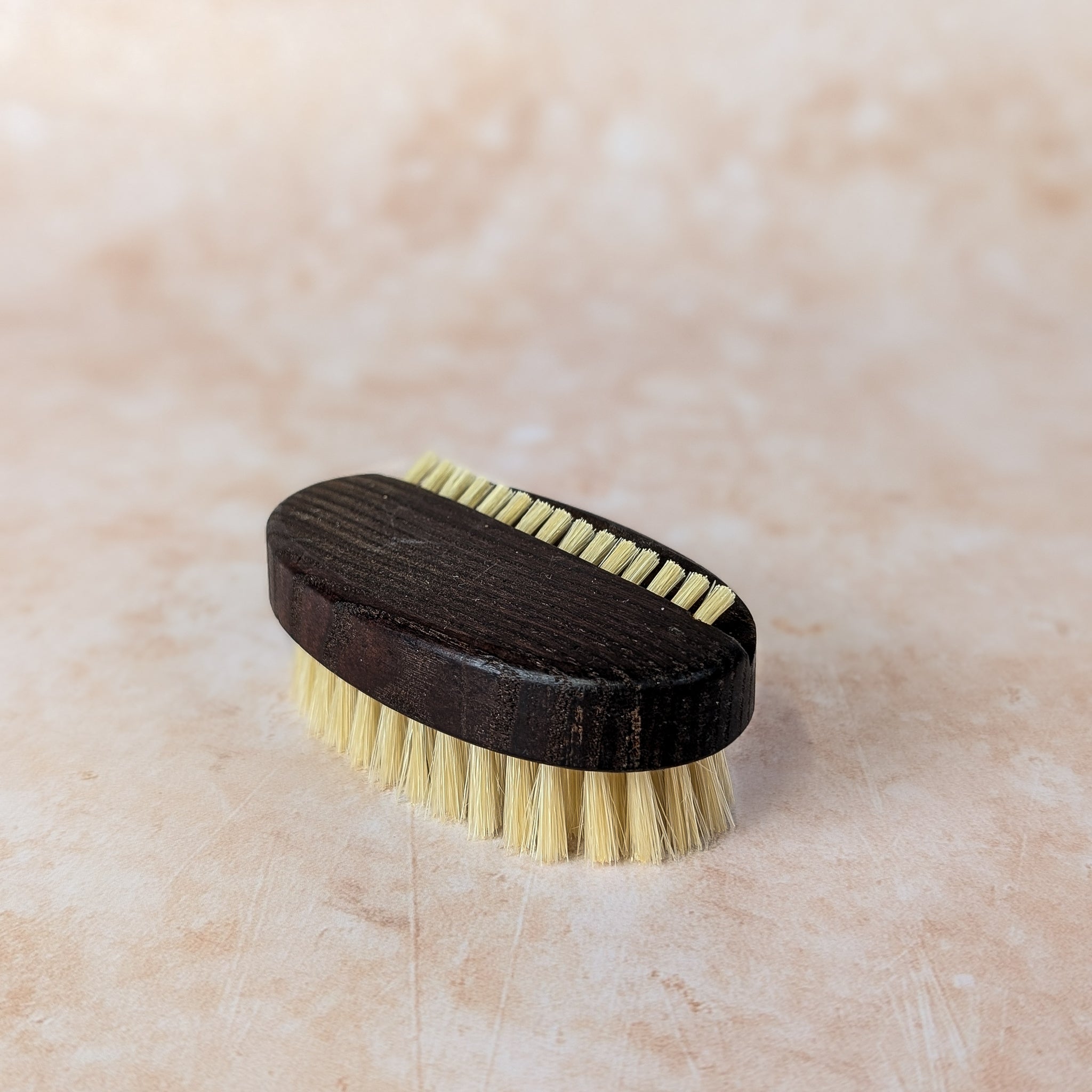 Brass brush with wooden handle on a beige surface