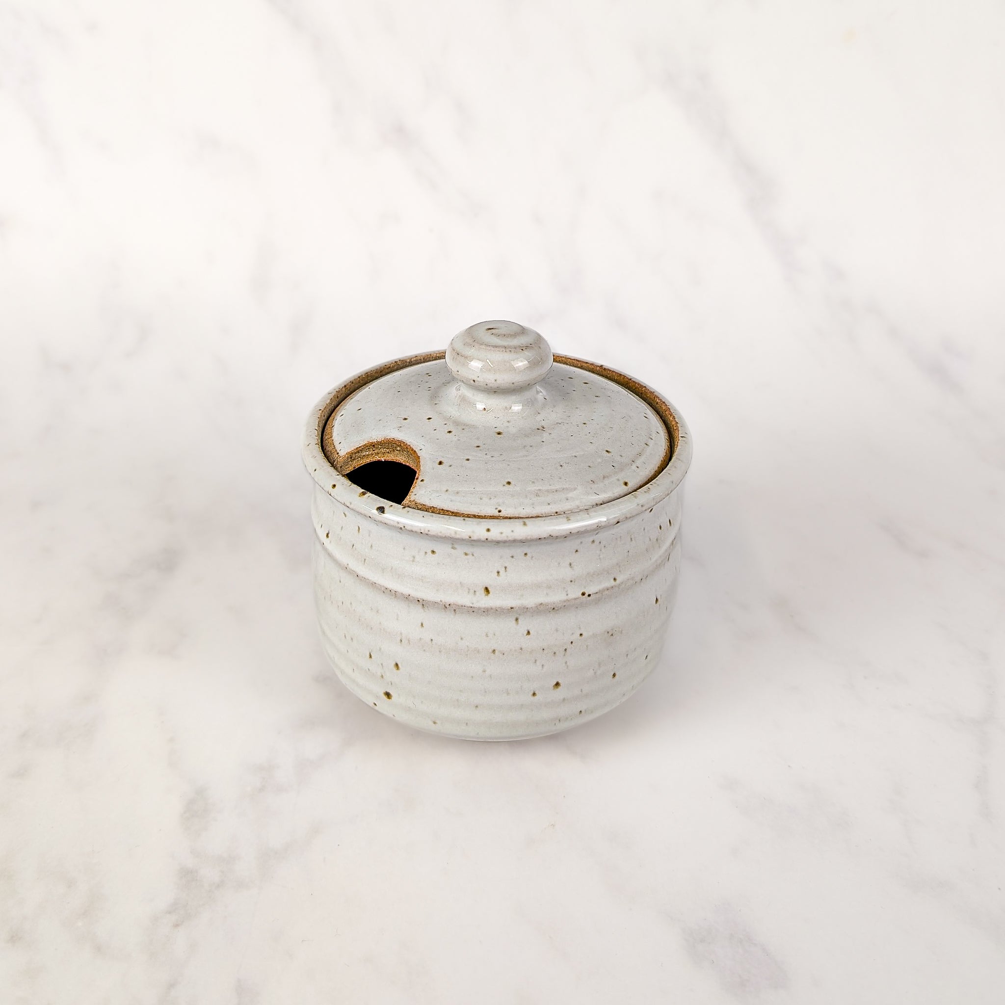White ceramic jar with brown speckles on a white background