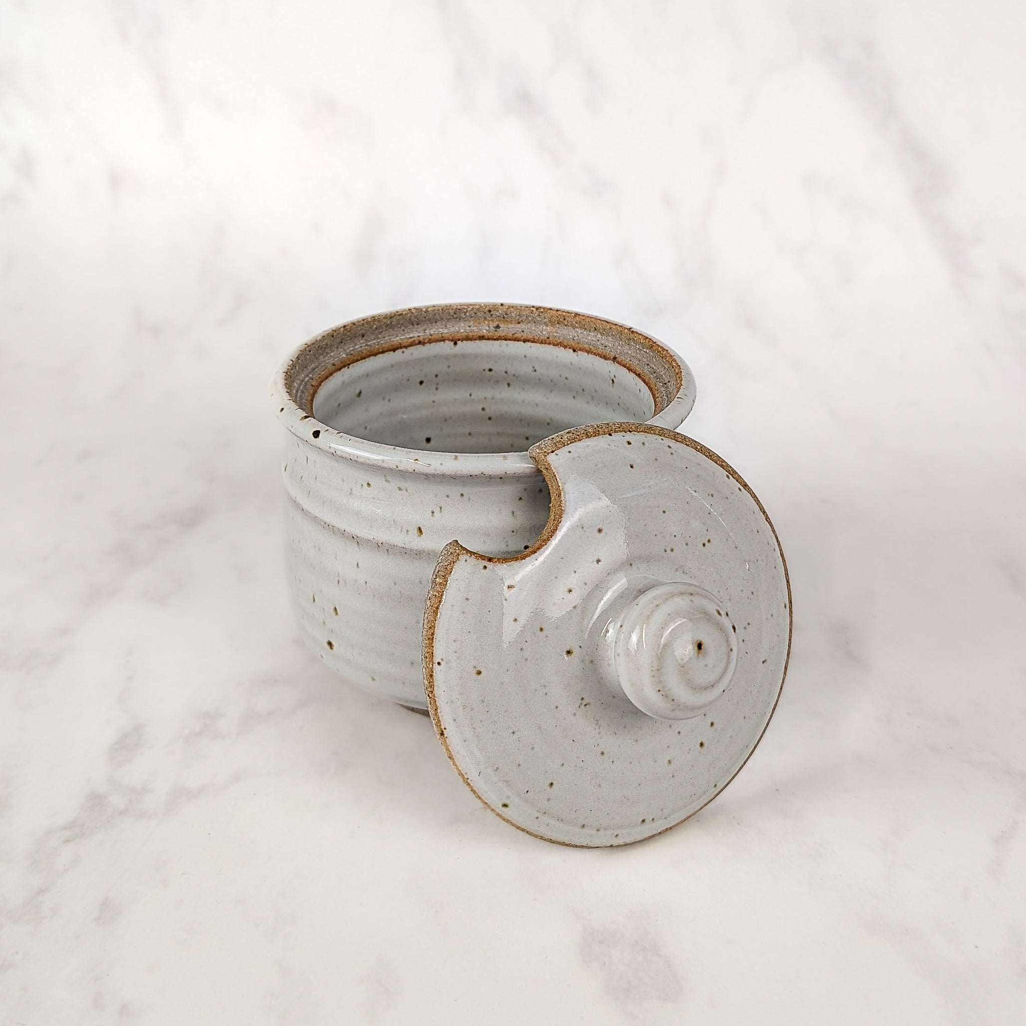 Speckled ceramic jar with lid on a white background