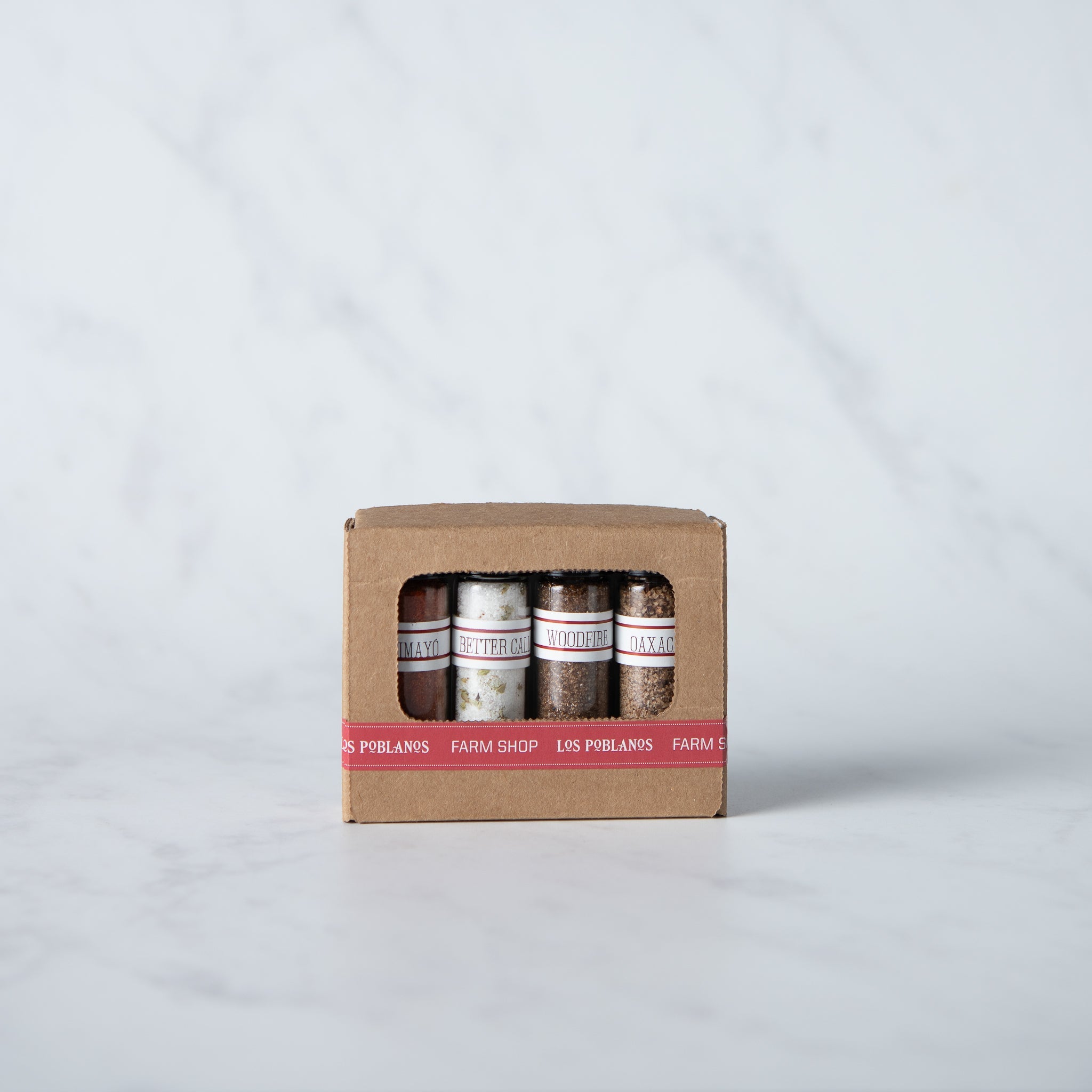 Box of Los Polanos Farm Shop spice jars on a light gray background