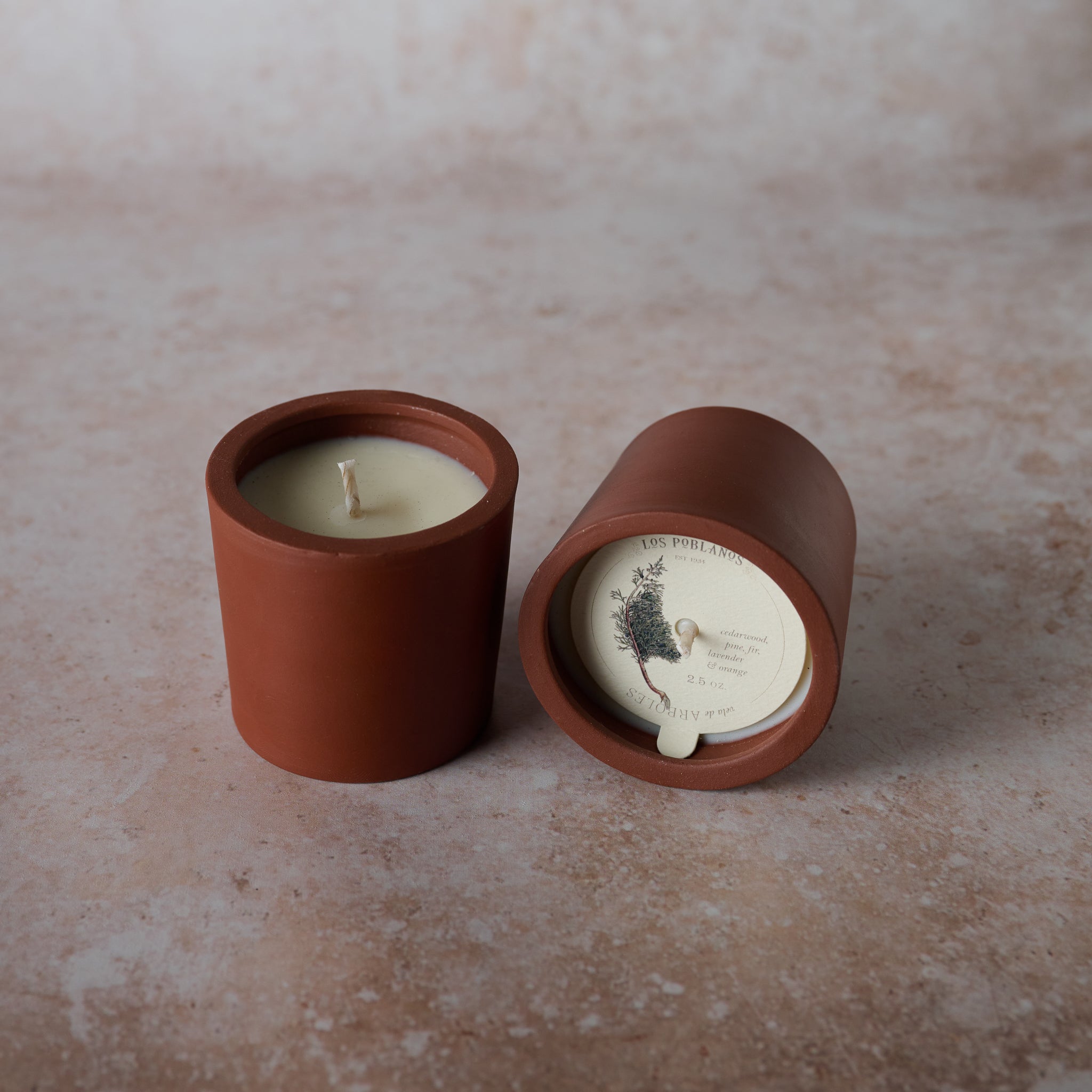 A terracotta candle vessel, on a neutral background.