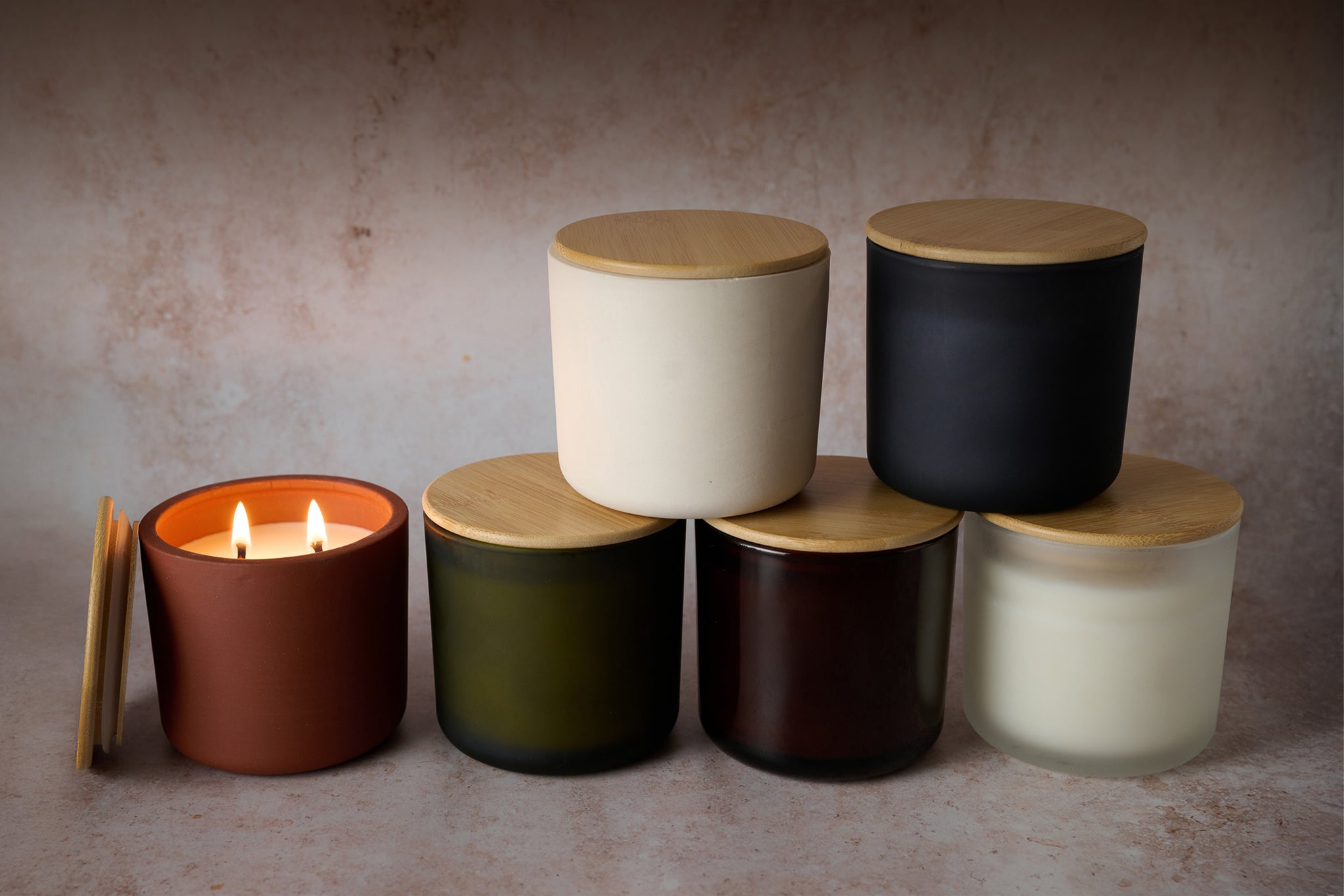 Set of cylindrical containers with wooden lids on a neutral background