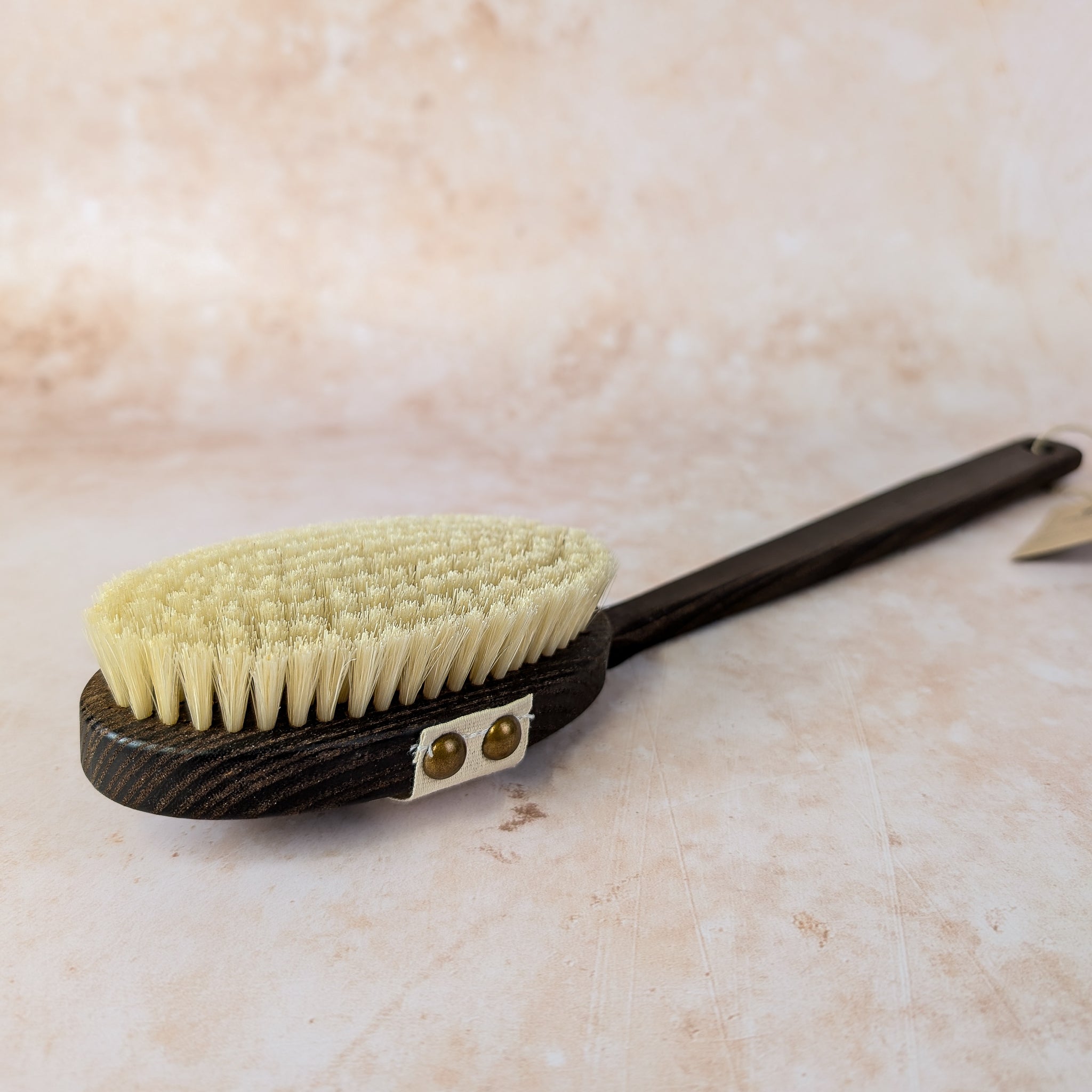 Brush with a black handle and green bristles on a beige surface