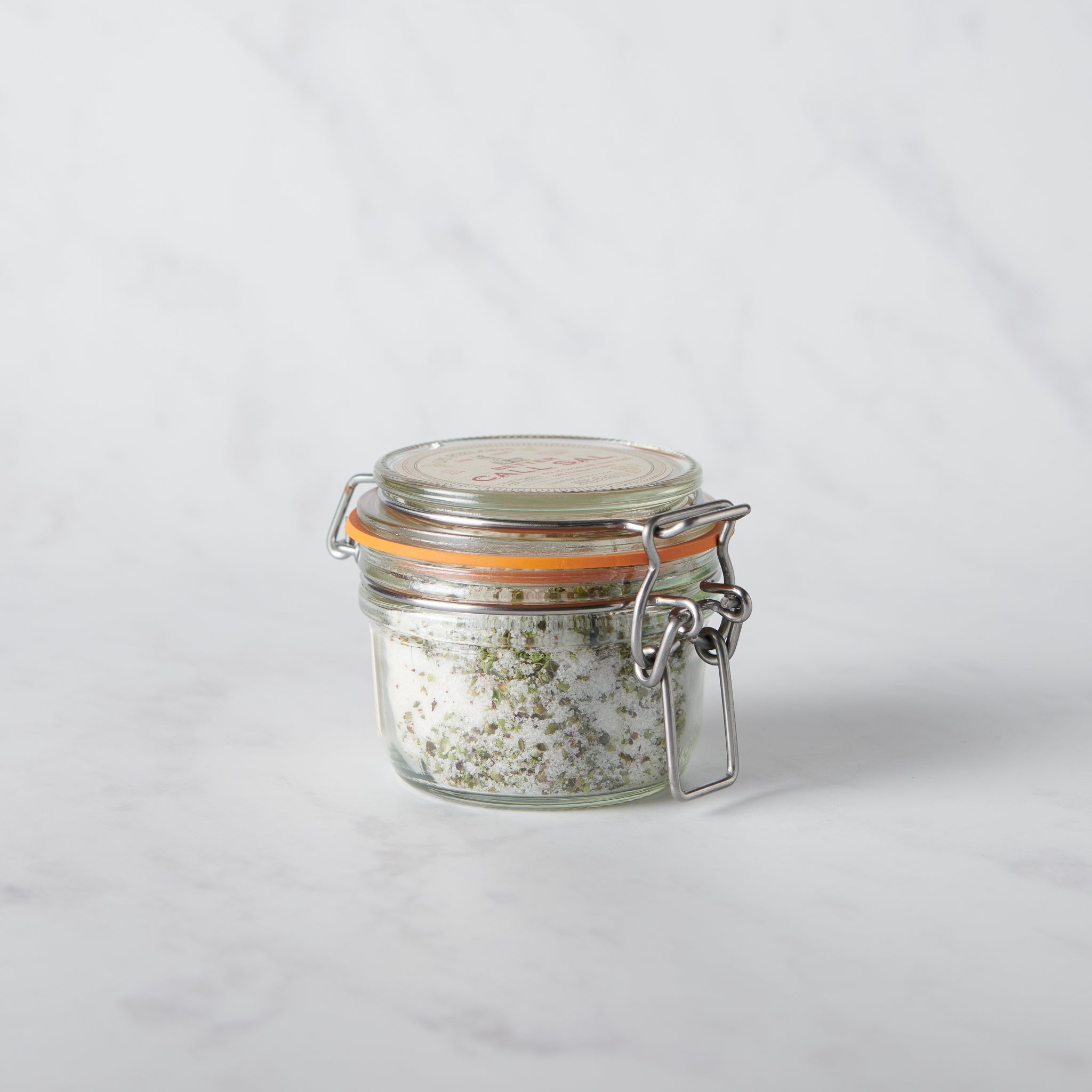 Glass jar with a metal clasp full of salt on a white background