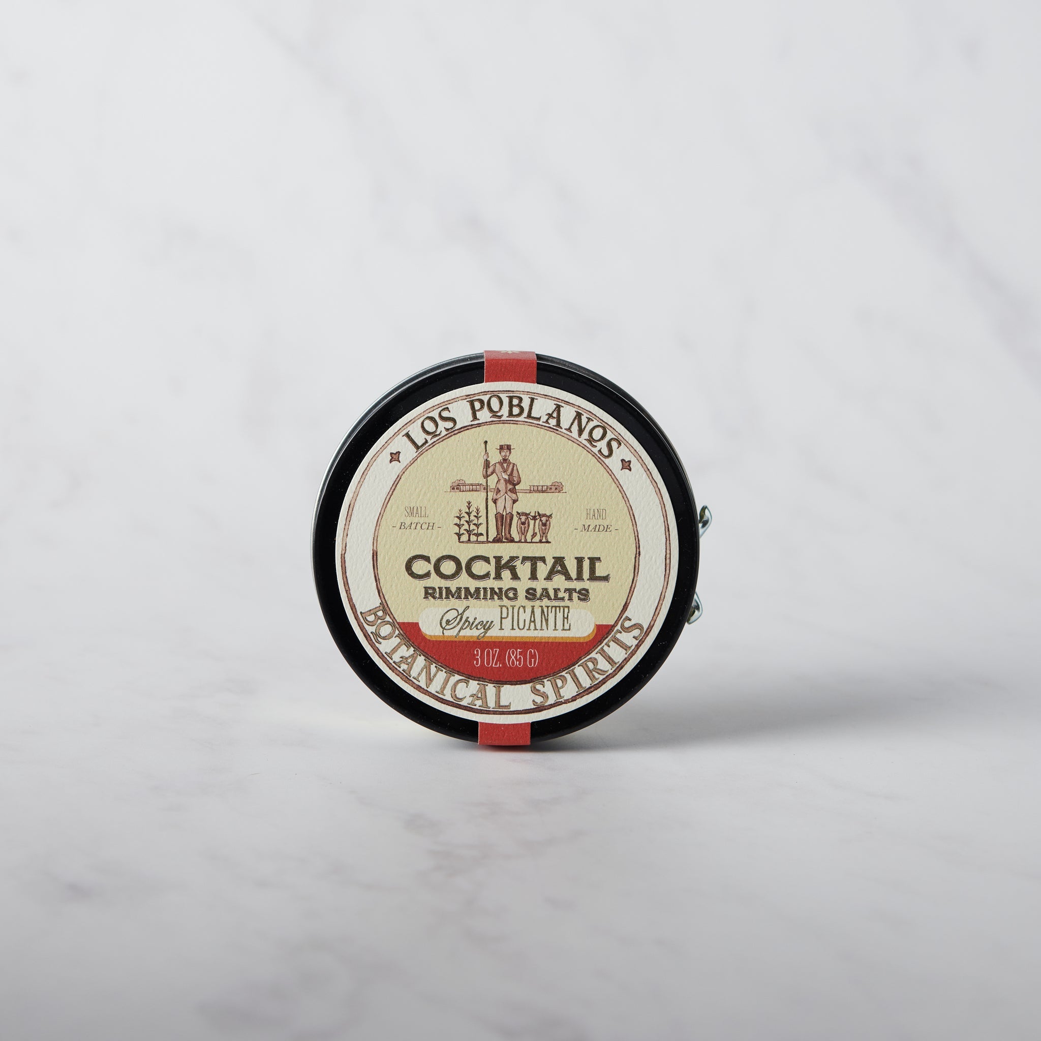 A round tin container of Los Poblanos Cocktail Rimming Salt - Spicy, with a label featuring an illustration of a pepper and text detailing the product.