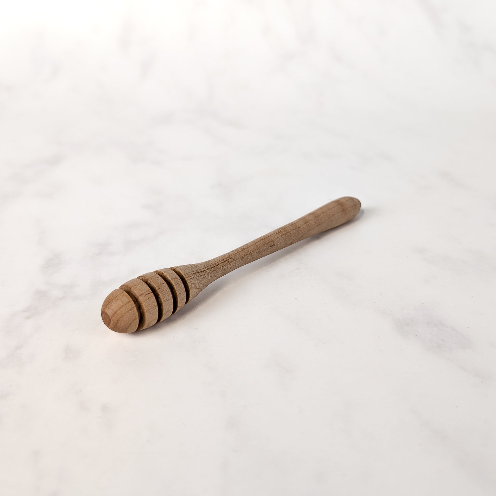 Wooden honey dipper on a white marble surface