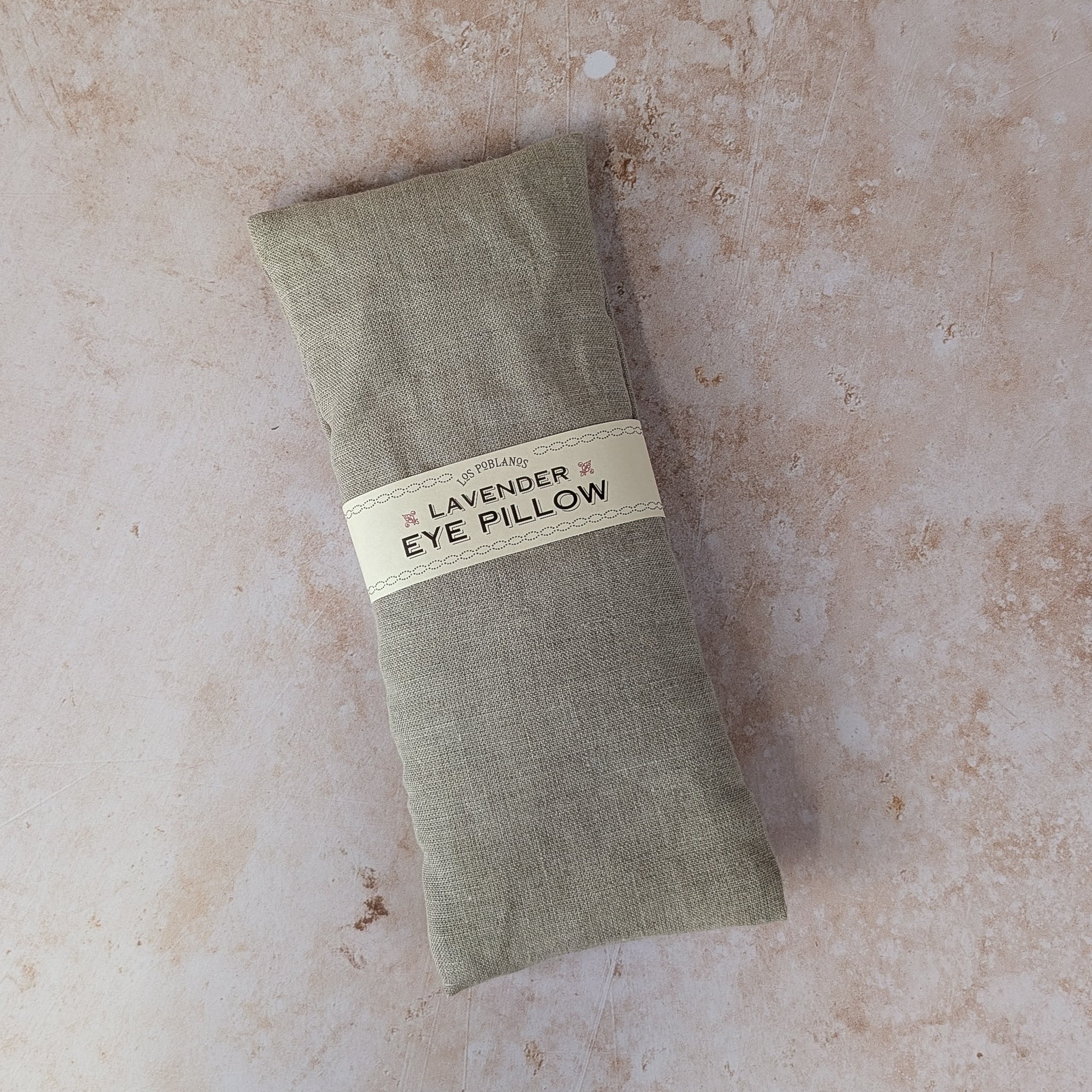 A gray Lavender Eye Pillow with a label wrapped around the center.