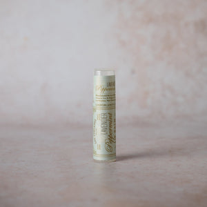 A tube of Lavender Peppermint Lip Balm against a pink background.