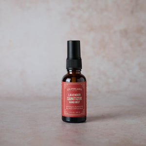 A 1 oz amber glass bottle with a black spray nozzle labeled Lavender Sanitizer Hand Mist.