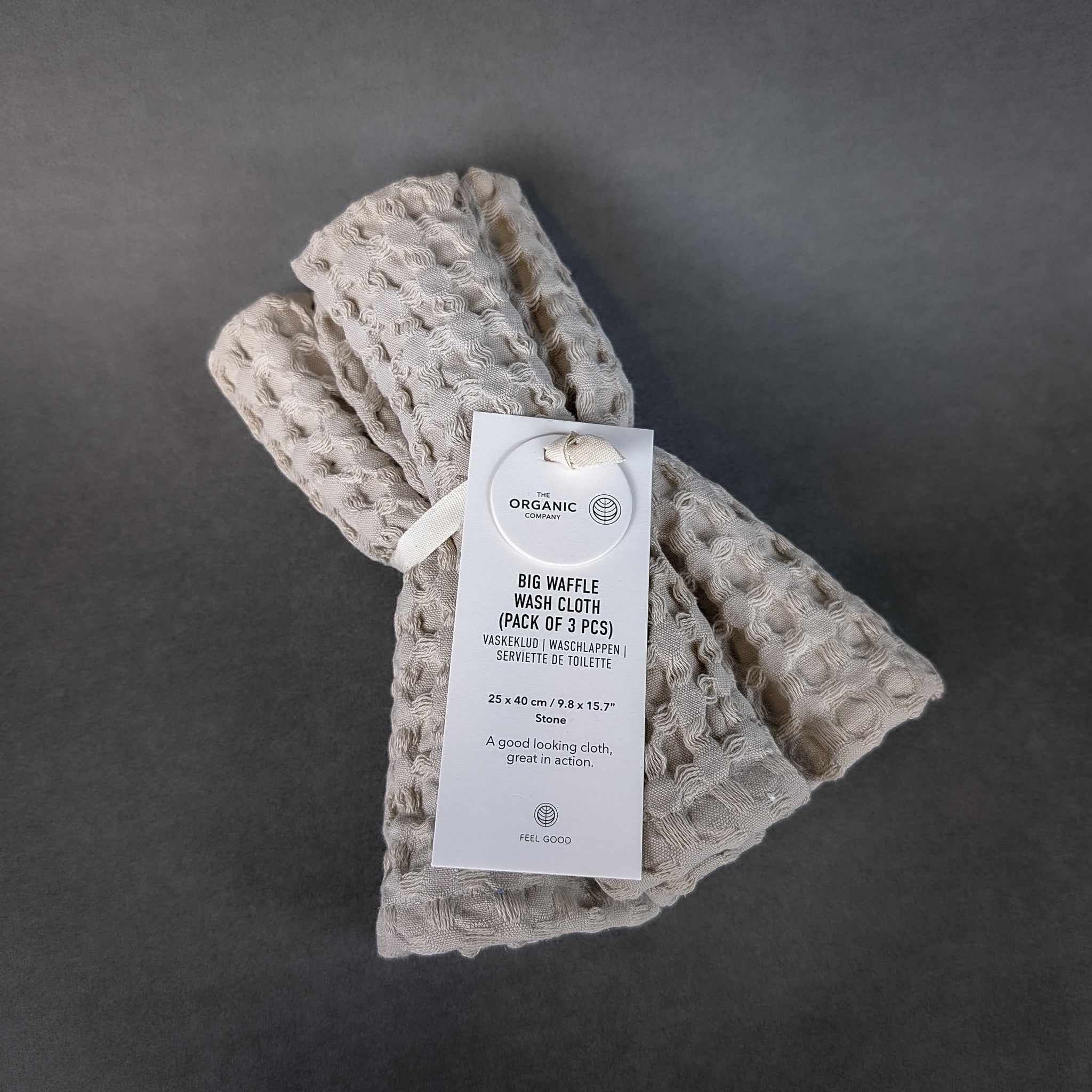 Stack of three waffle-weave bath wash cloths made from GOTS-certified organic cotton, featuring subtle neutral colors and branded tag.