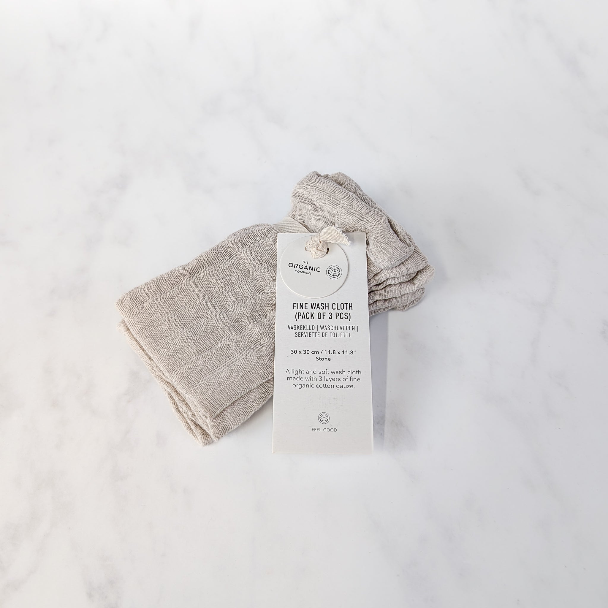 Folded beige washcloth with a tag on a white background
